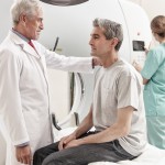 Senior male doctor explaining CT scanner exam to man in 40s. Fem