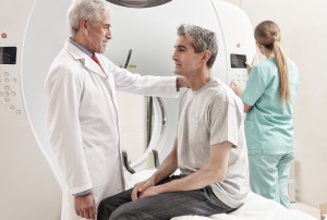 Senior male doctor explaining CT scanner exam to man in 40s. Fem