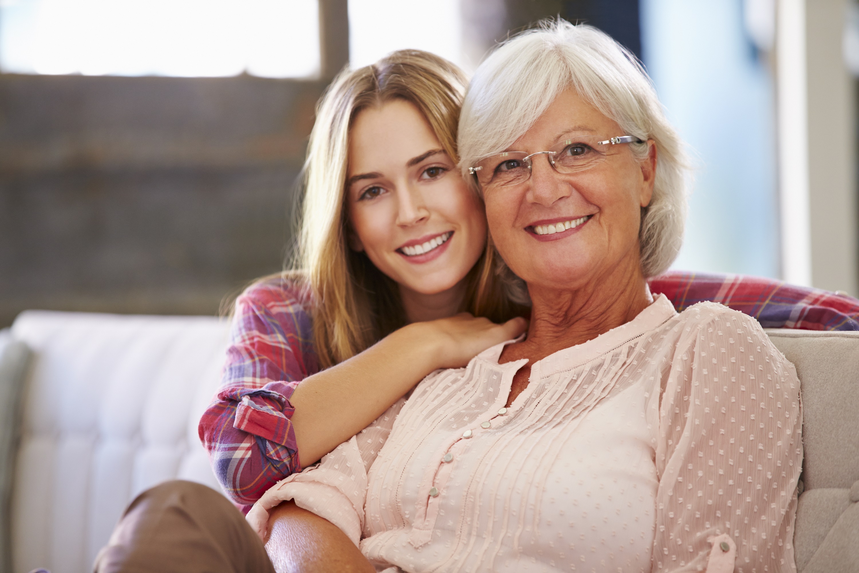 Grandmother With Adult Granddaughter Relaxing On Sofa